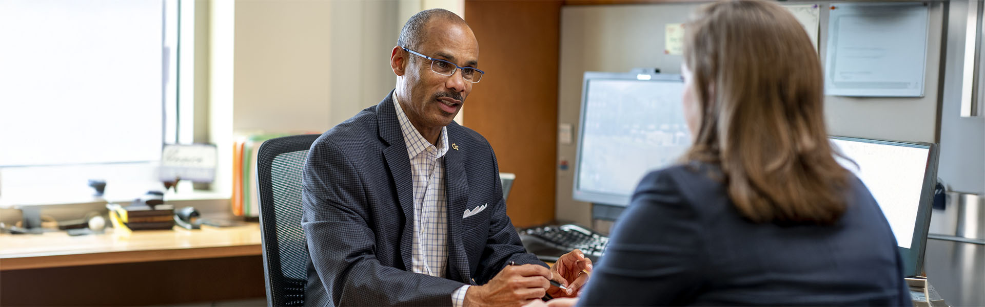 Man consulting with female student at office desk