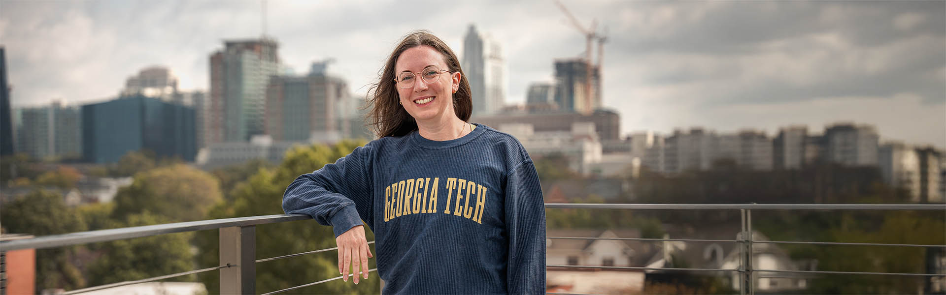 Female student wearing a Georgia Tech sweatshirt overlooking midtown Atlanta