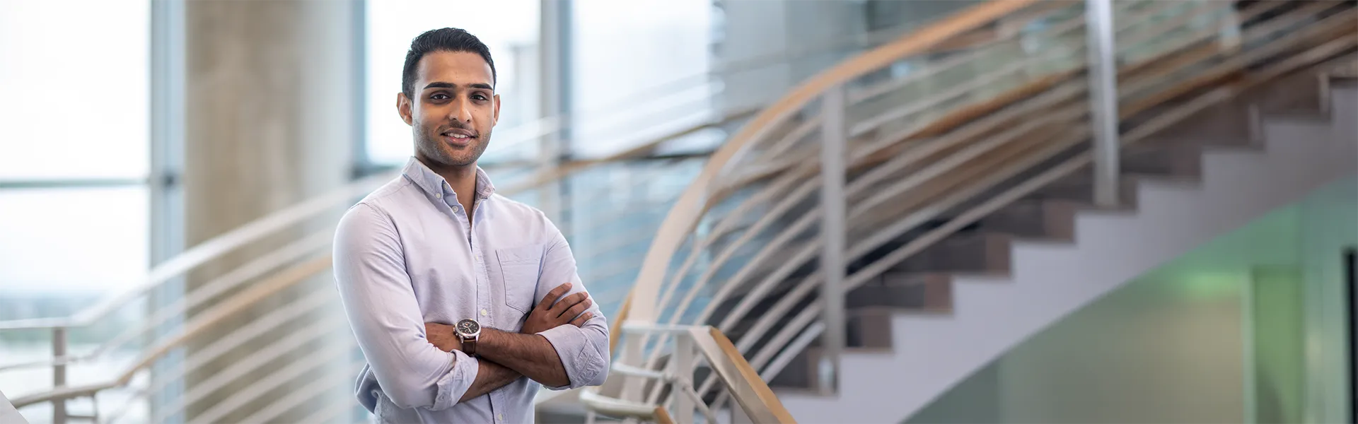 PhD Student standing in front of spiral staircase