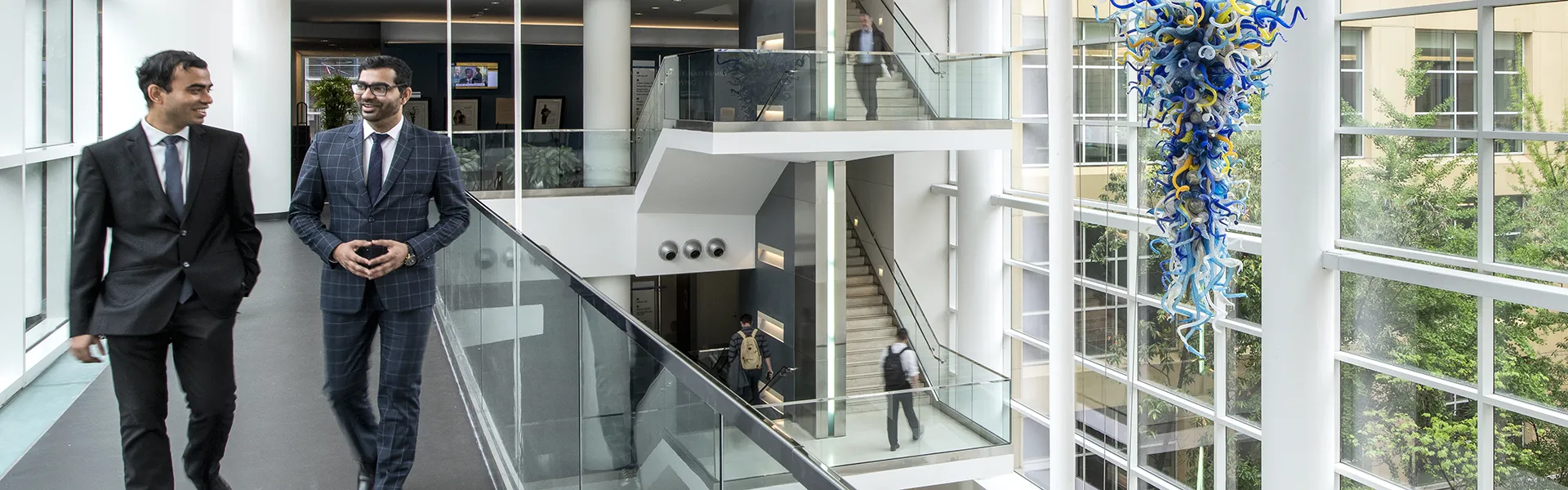 Two PhD Student walking on atrium bridge inside Scheller