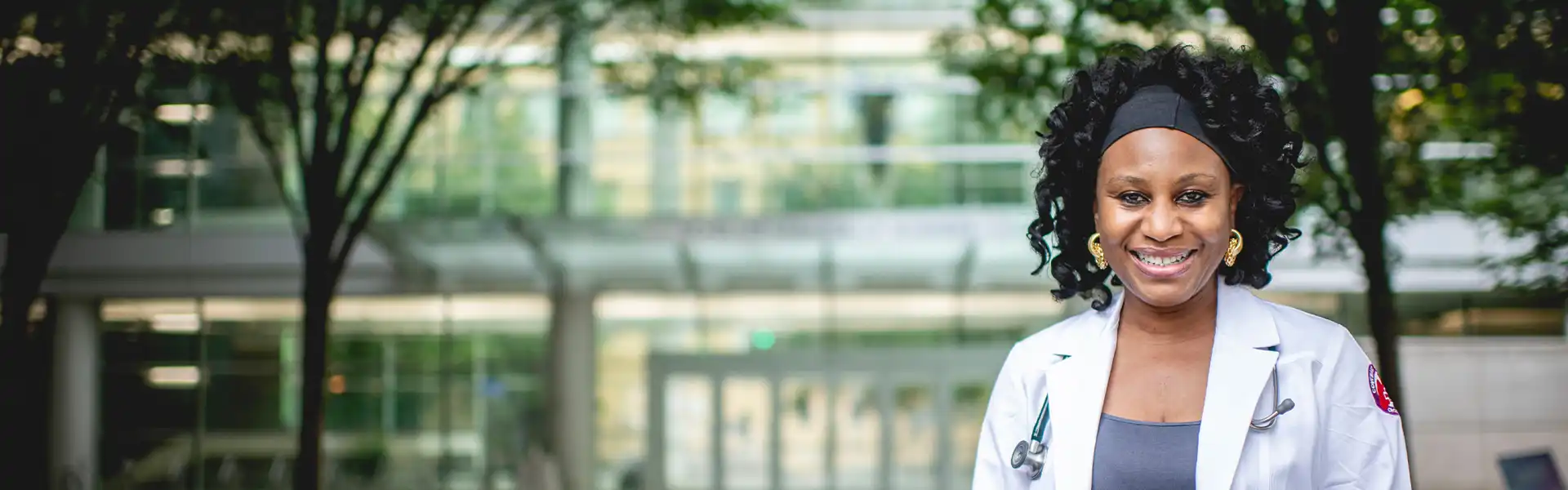 Executive MBA student stands in front of the Scheller College of Business wearing a white lab coat
