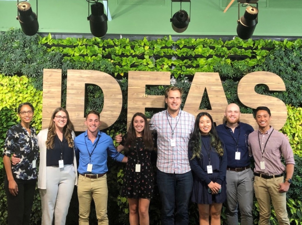 Scheller alumni gather in front of Accenture's 'ideas' wall that features living plants
