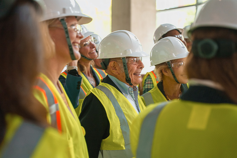 A group of people gather dressed in bright vests and hard hats