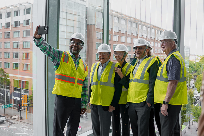 Five people smile dressed in hard hats and flourescent vests 