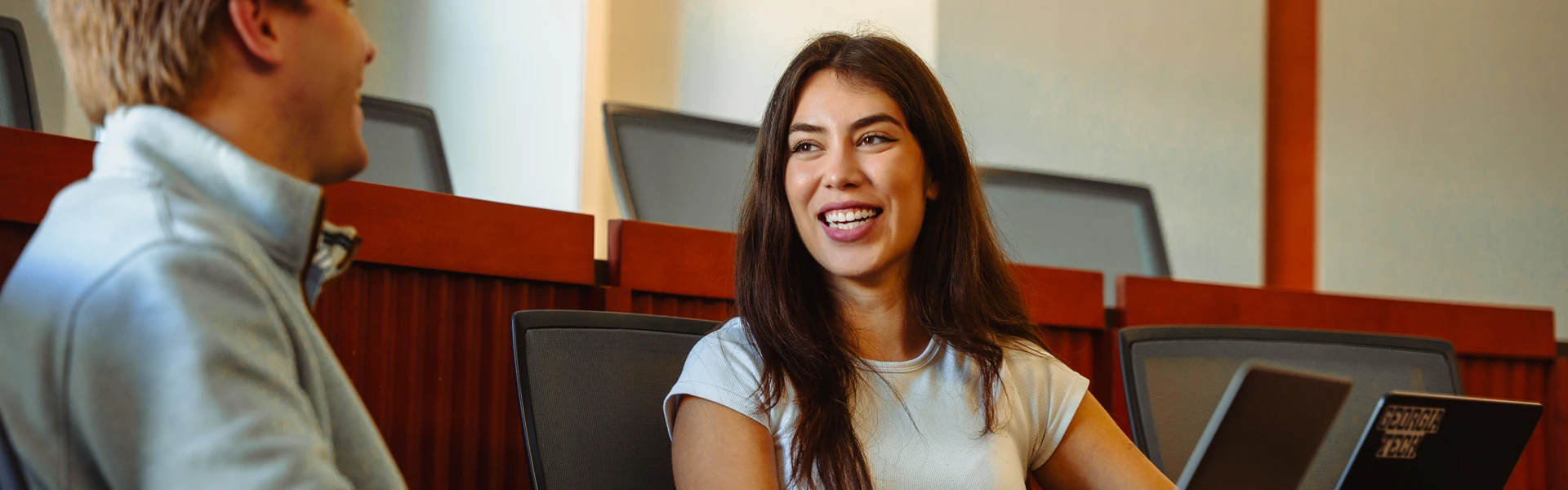 student sits with computer in a classroom
