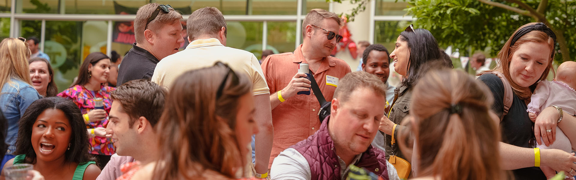 Large group of MBA students and alumni gathering outside eating and mingling
