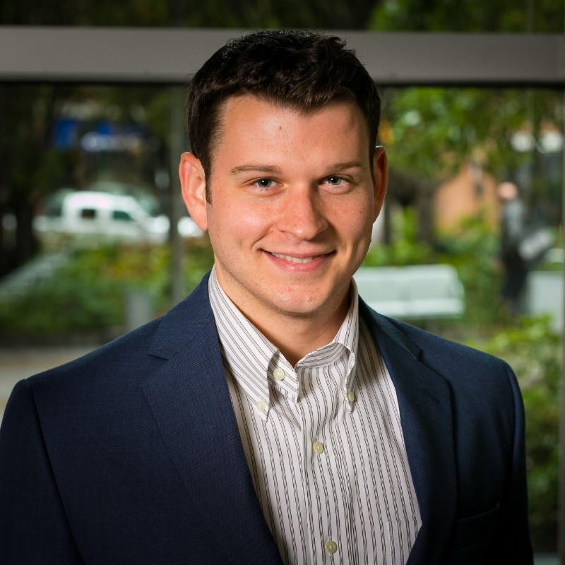 Jay Arcement, Evening MBA '16 smiles in a black suit coat