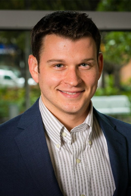 Jay Arcement, Evening MBA '16 smiles in a black suit coat