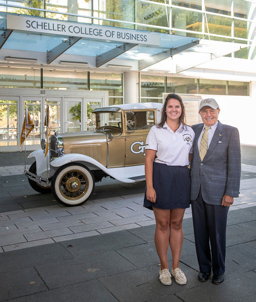 Ernest Scheller Jr. poses with business major Hannah Todd in front of his namesake College.