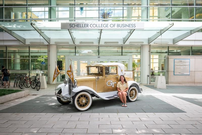 Hannah Todd poses with the Ramblin' Wreck in front of Scheller College of Business.