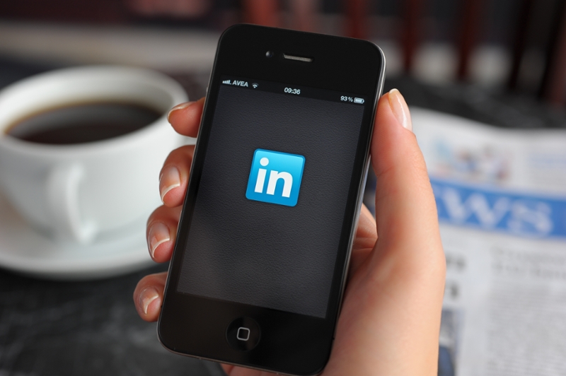 A hand holding a cell phone with the LinkedIn app