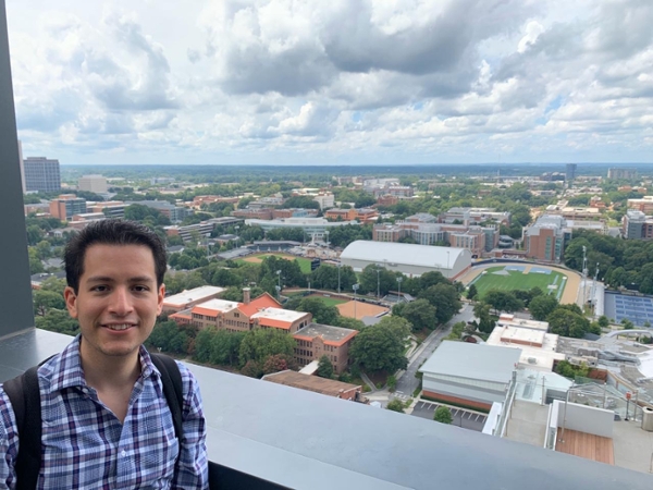 Luis Trejo, a Full-time MBA student stands next a view of the Atlanta skyline. 