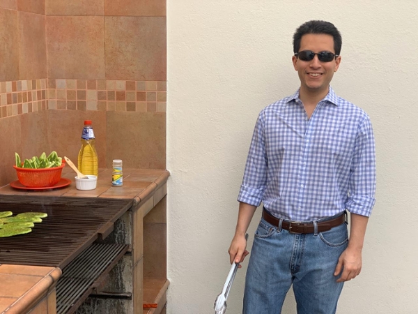 Luis Trejo, a Full-time MBA student stands next to a grill. 