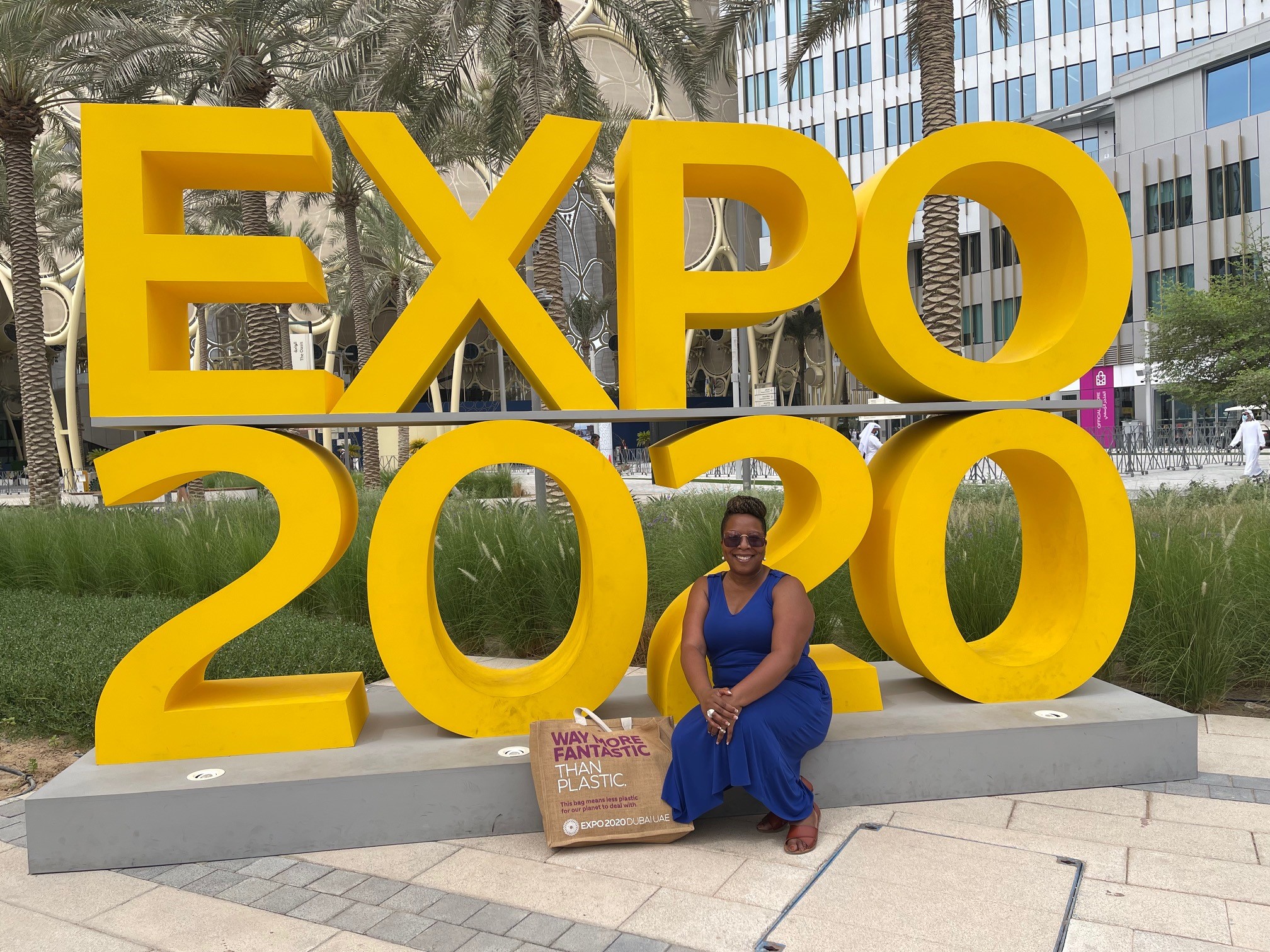 A student sits in front of a sign that says Expo 2020