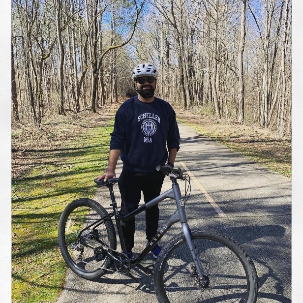 Full-time MBA student Akshay Verma stands next to his bike on a trail