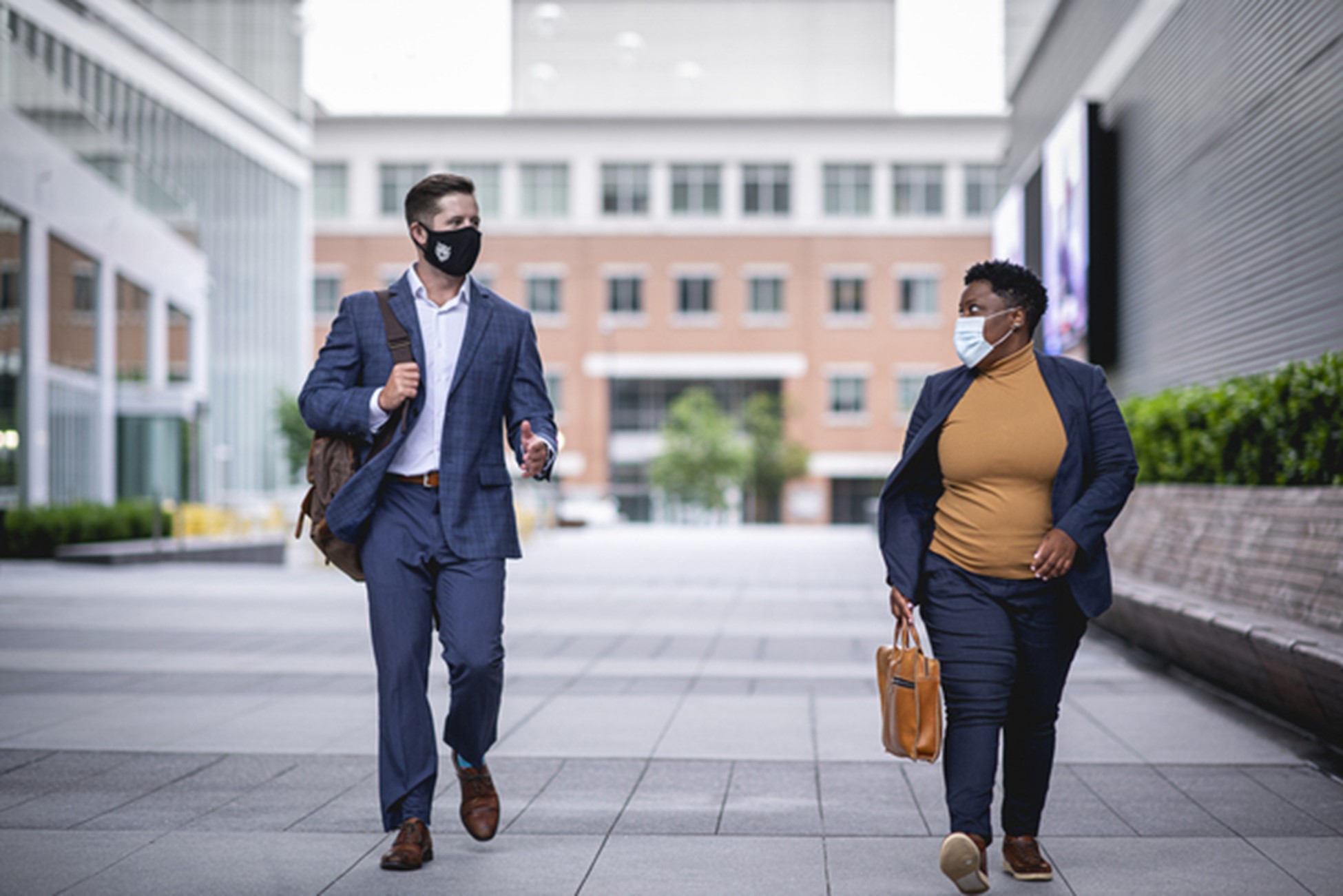 MBA students Jarrod Snell and Angel Daniels walk down a sidewalk talking to each other.