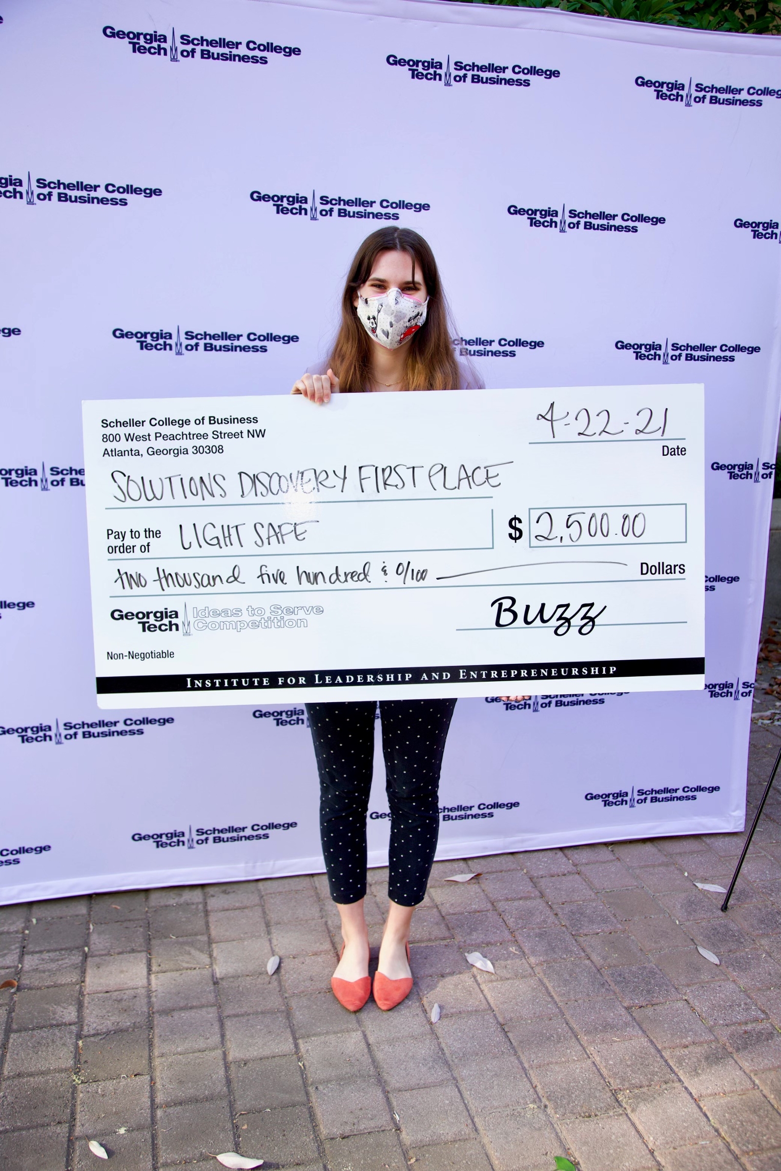 A Georgia Tech student holding up a large check after winning the Solutions track at the Ideas 2 Service competition.