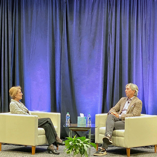 Man and woman sitting in armchairs on stage