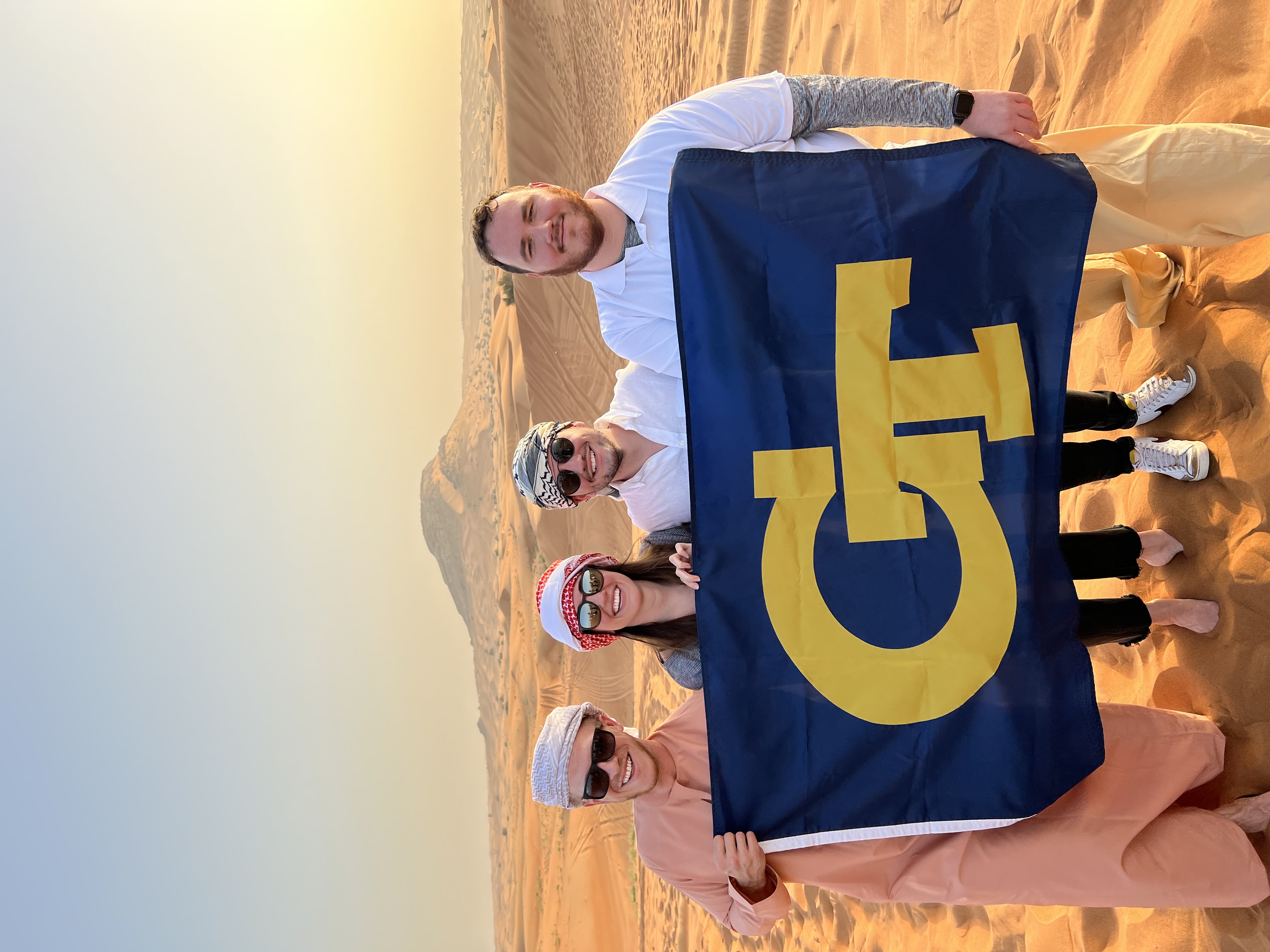 A group of students hold a Georgia Tech flag in the desert