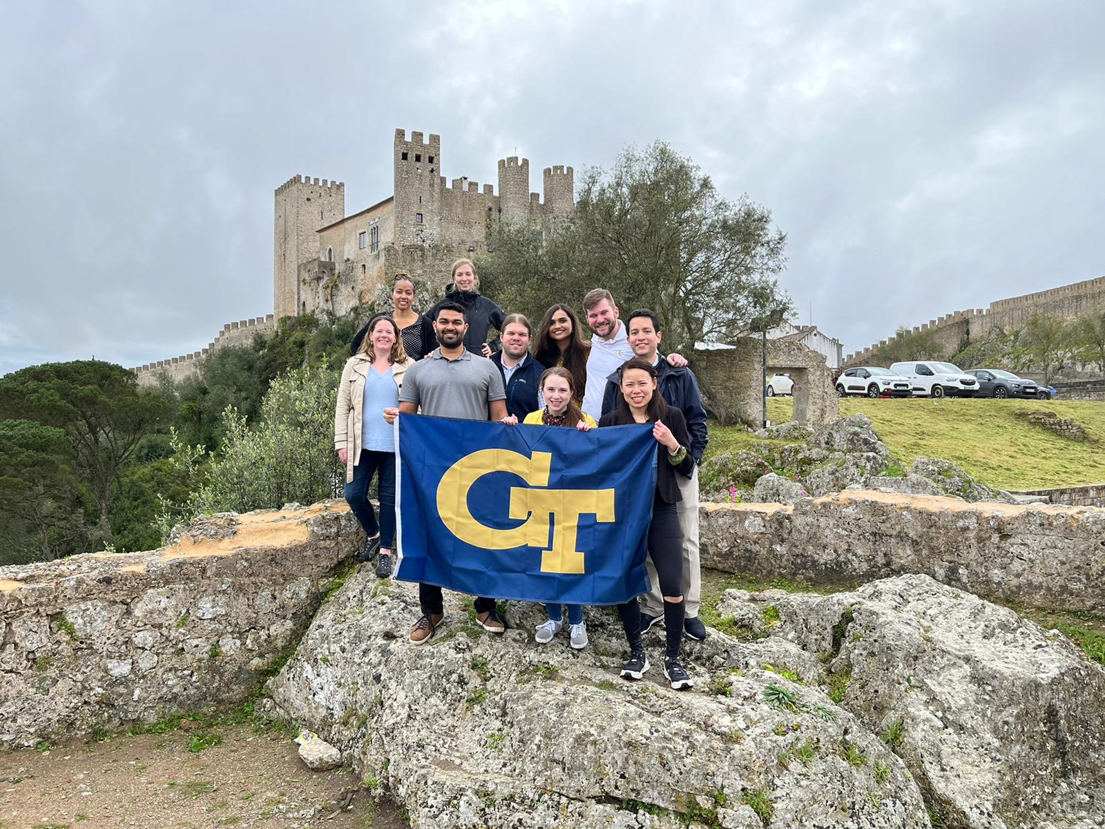 Students hold a GT Flag in front of a castle