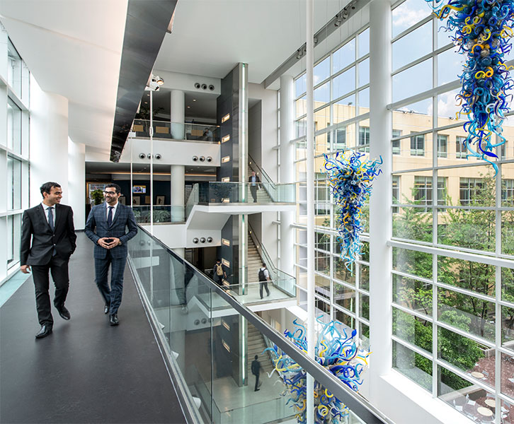 Two men walking in the Atrium of the Scheller building