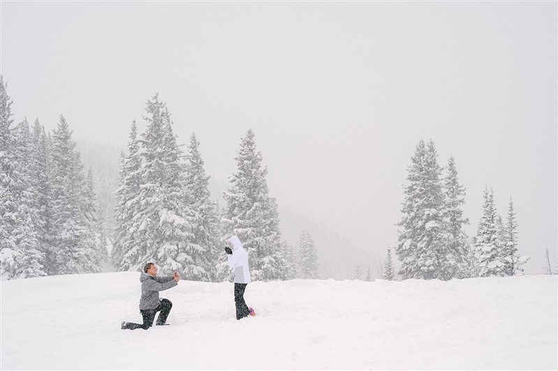 A man is proposing to a woman in the snow.