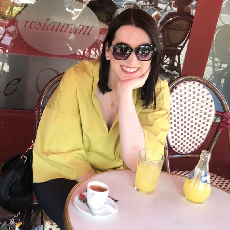 Kelly Pierce, Evening MBA ‘23 sits at a table in Paris, France.