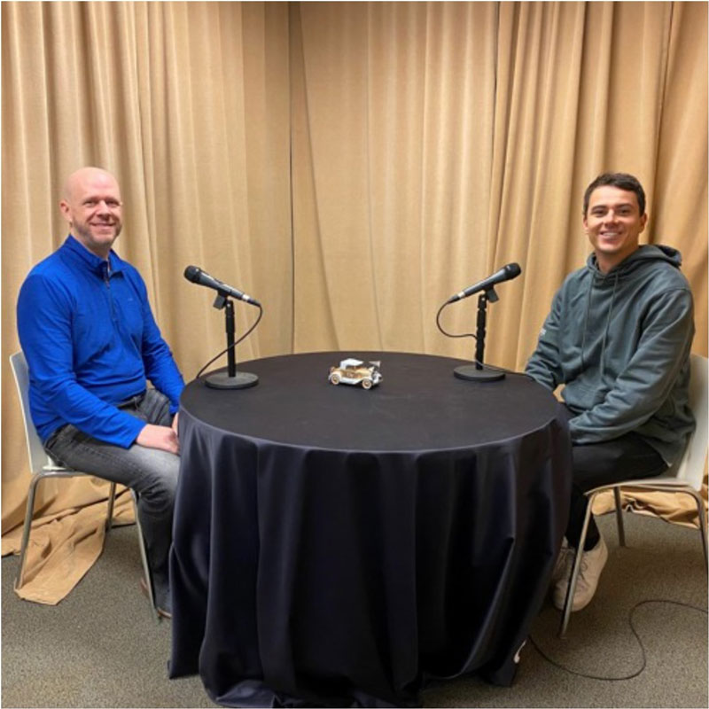 MBA student Leo Haigh and faculty member Michael Buchanan sit around a table, ready to record a podcast.