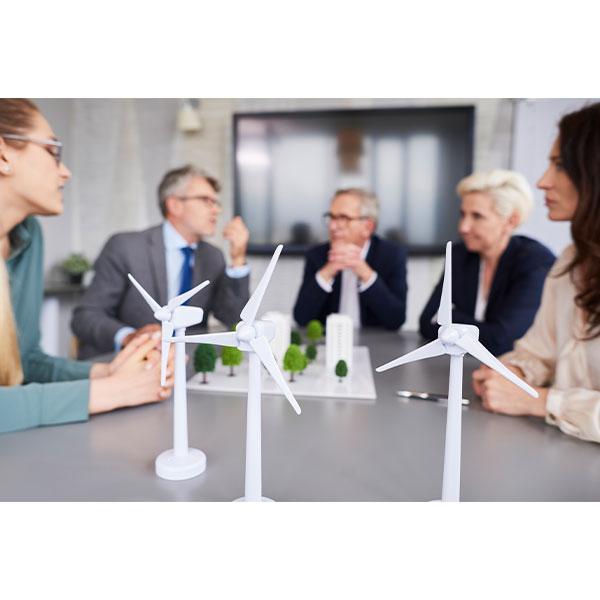 Models of windmills sit on a meeting table surrounded by stakeholders   