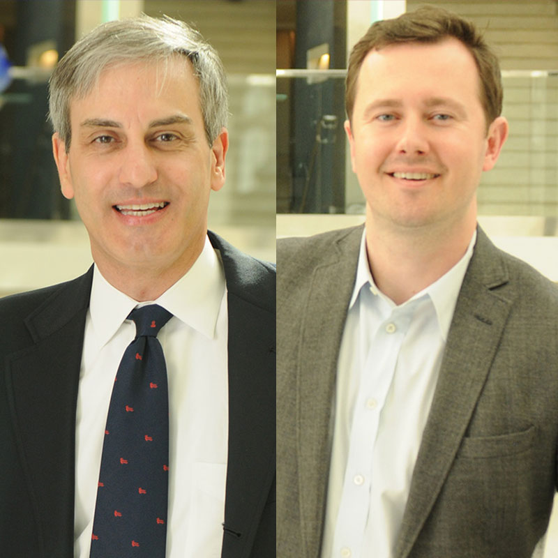 Scheller College of Business professors, Alex Oettl and Jonathan Giuliano, stand smiling in suit coats