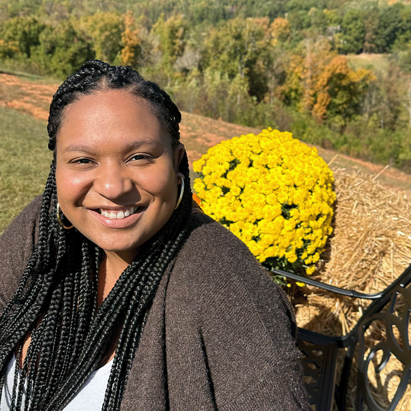 Stacy Feeling, Full-time MBA ‘23, sits outside in front of yellow flowers