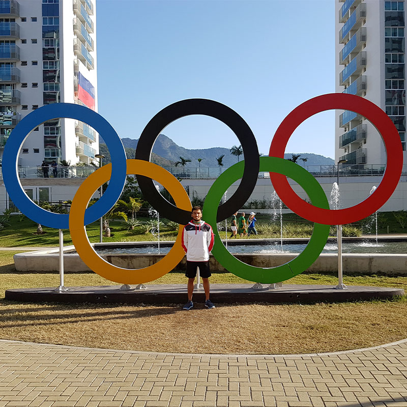 Andrew Chetcuti standing in front of the Olympics rings in Rio in 2016. 