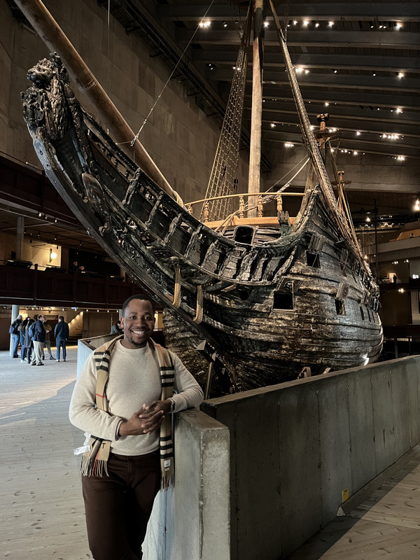 Student posing next to boat