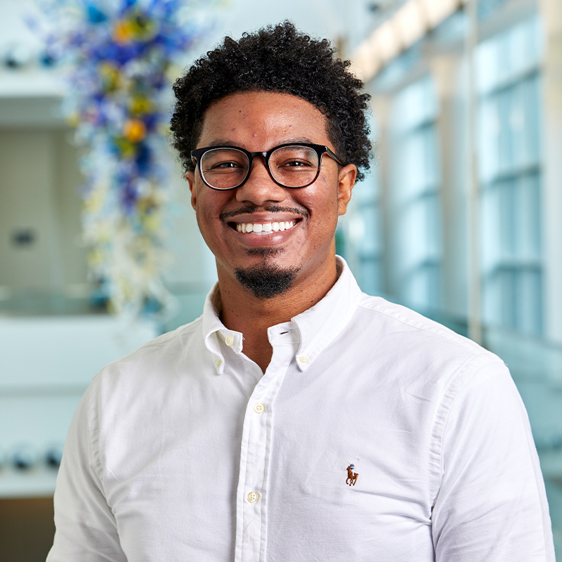 Charles Moody, Scheller Evening MBA ‘24, stands in the Scheller College of Business atrium; a glass sculpture hangs behind him.