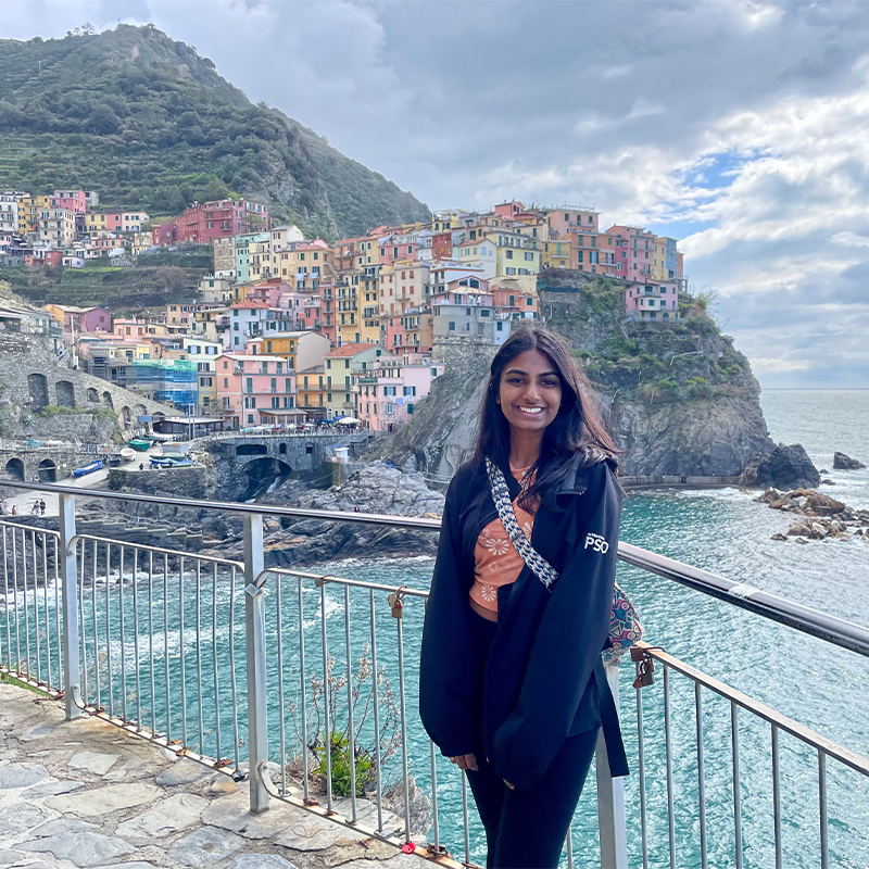 Ooha Edupuganti, Scheller Full-time MBA ’24, poses in front of a colorful coastal city. 