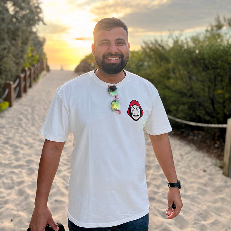 Rahul Mishra, Scheller Full-time MBA ’24, stands on a sandy beach in front of the ocean during a sunset.