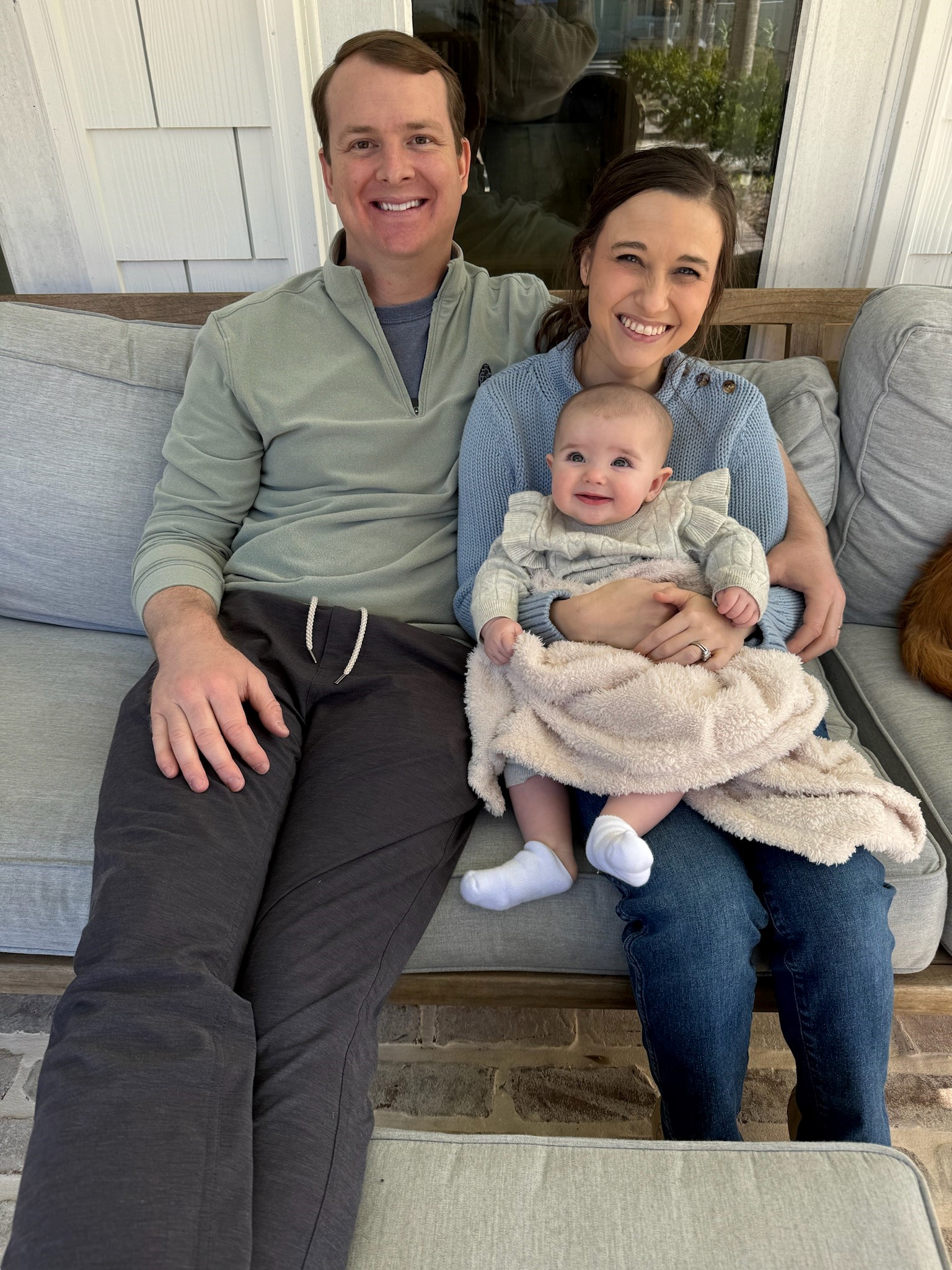 Ross Doelling, Scheller Full-time MBA ’24, sits on a couch with his arm around his wife and baby.