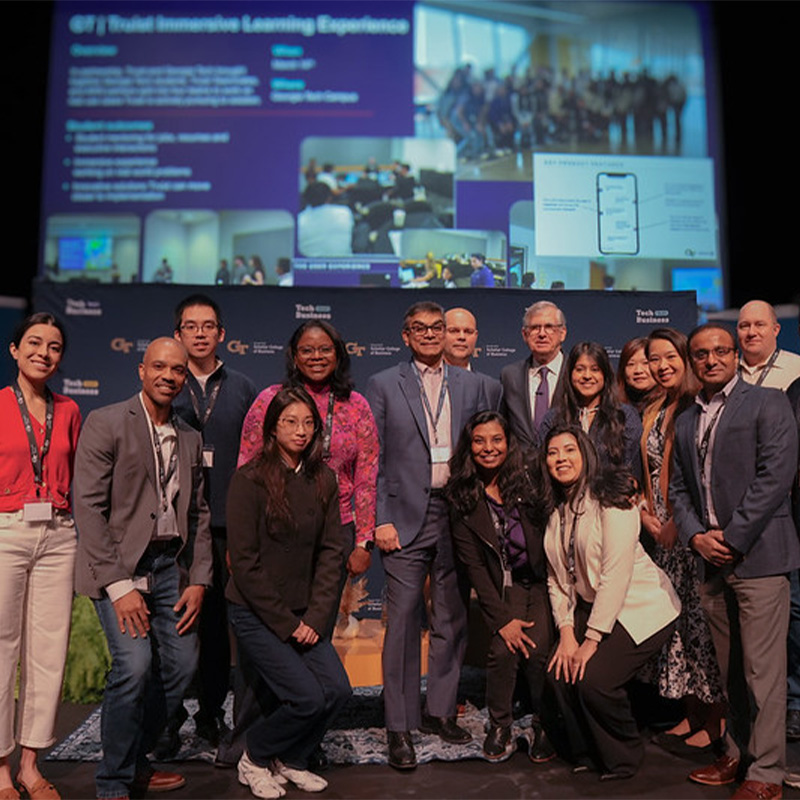 A group of women and men gather on a conference stage 