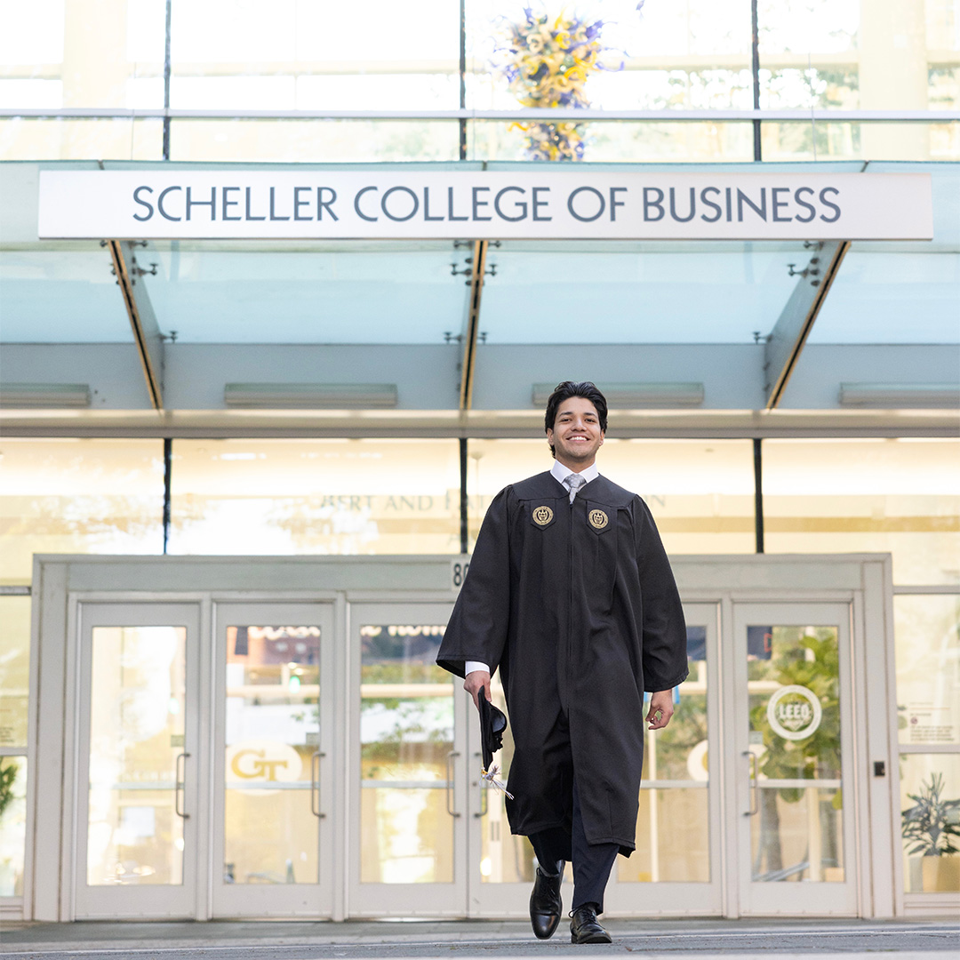 A Georgia Tech student faces away from the camera with their graduate regalia on