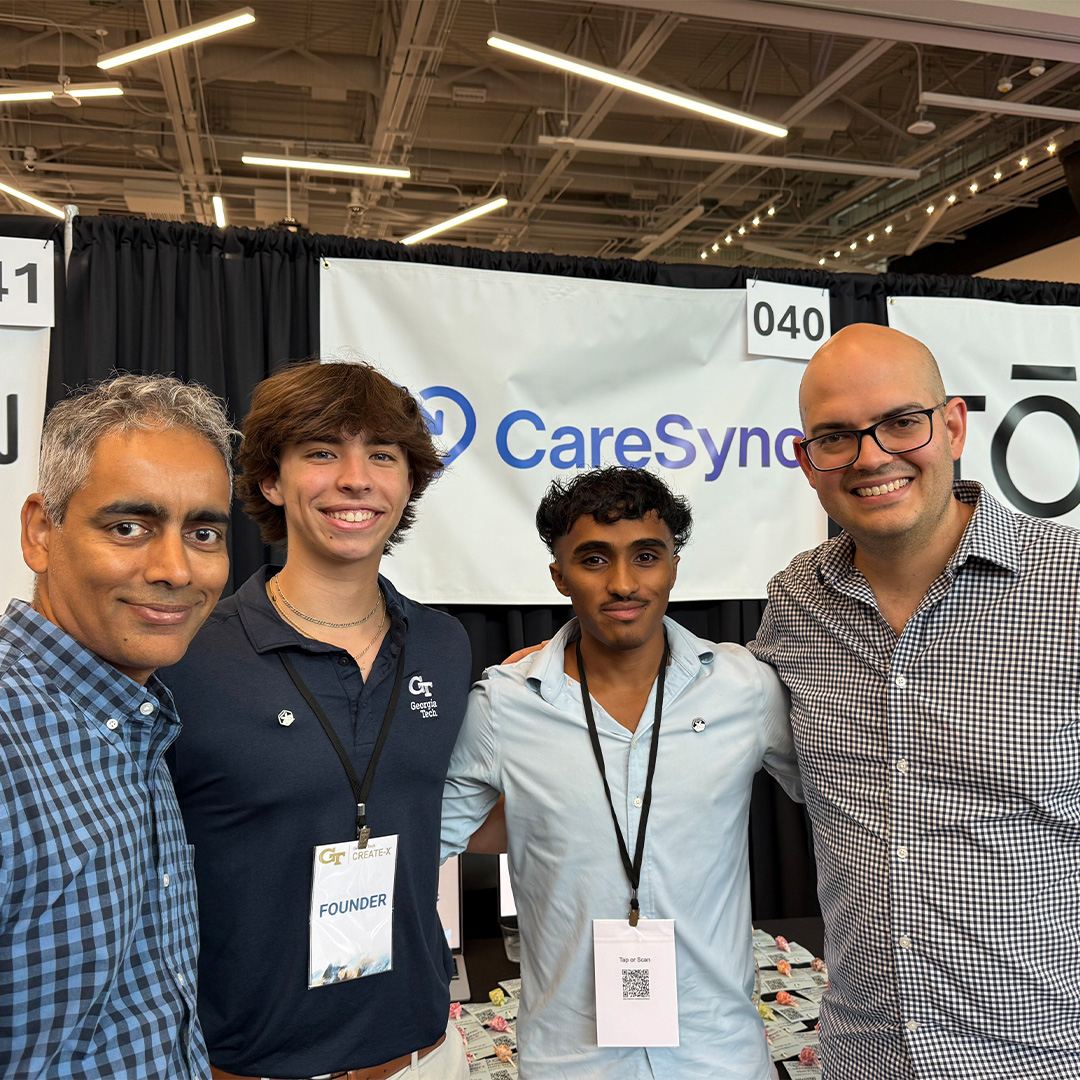 Karthik Ramachandran, Cooper Ciavola, Azan Khan, and Andre Calmon stand in front of a CareSync startup sign at a Georgia Tech event