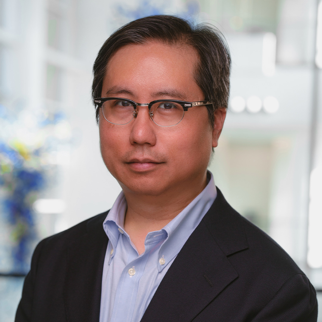 Jeffrey Valdez smiles wearing a dark suit and tie