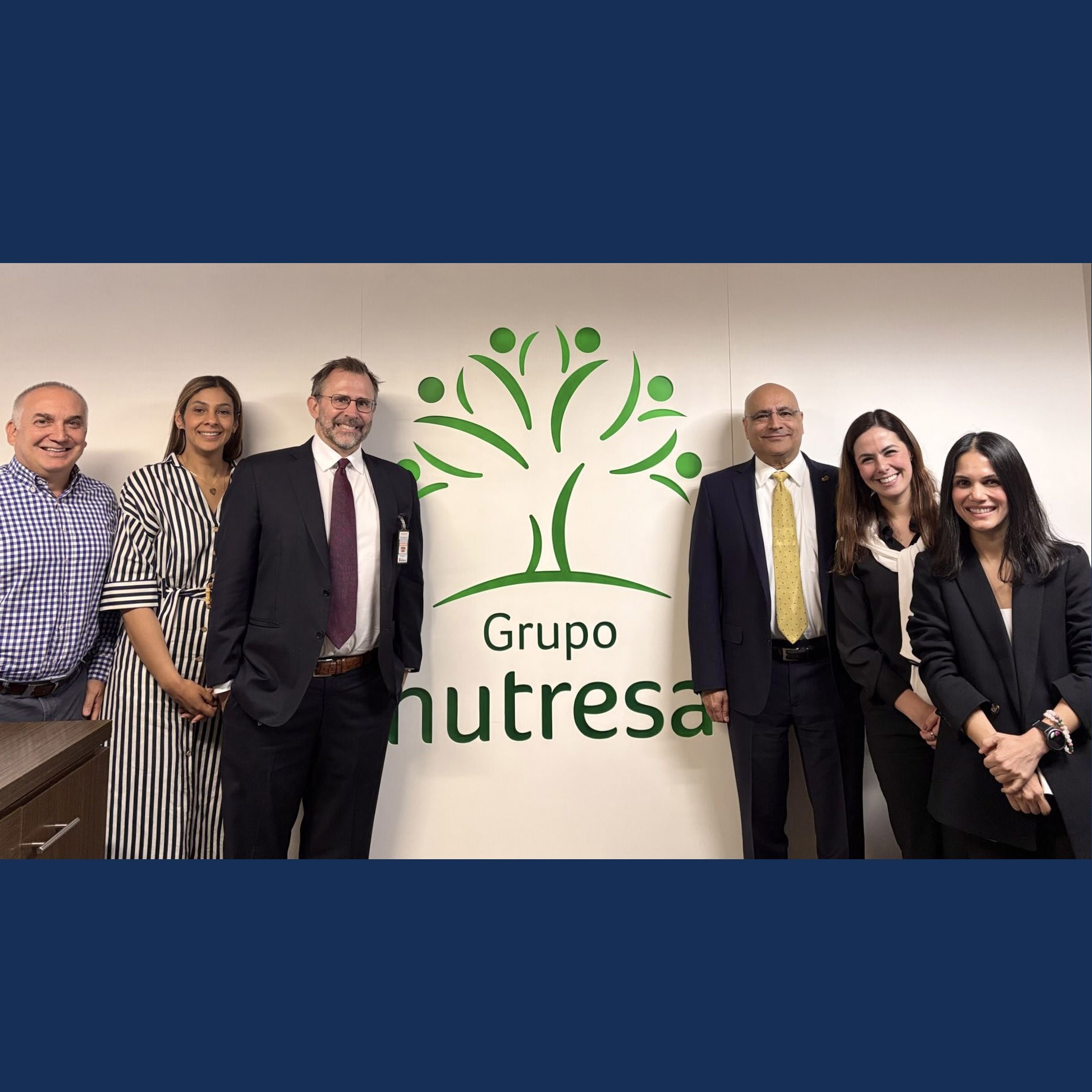 A group of women and men stand in front of a "Grupo Nutresa" sign