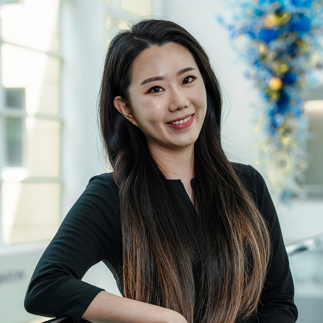 A woman dressed in black leans on a rail and smiles