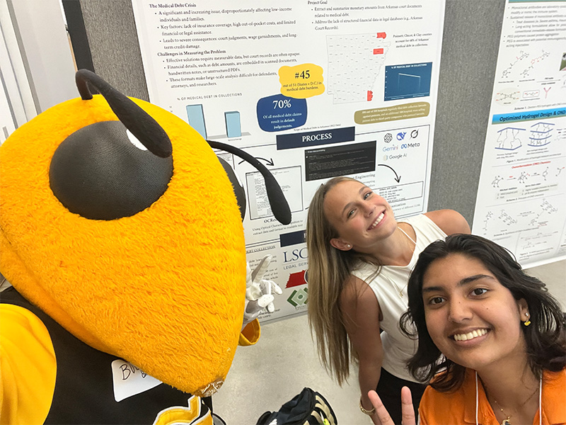 Katherine Hughes and Bratee Podder smile with Buzz, the Georgia Tech mascot