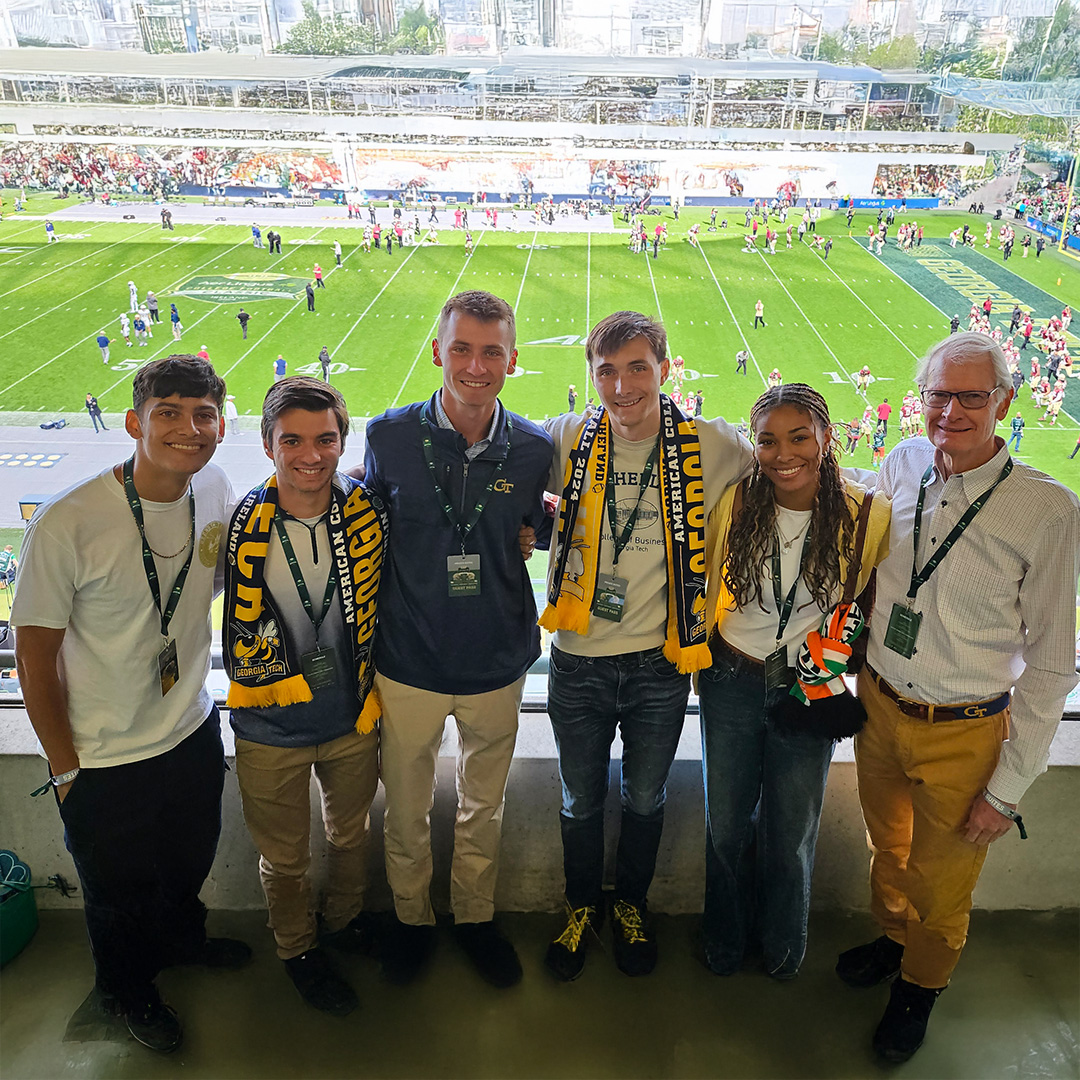  A group of Georgia Tech students and Dick Bergmark stand in front of a football field