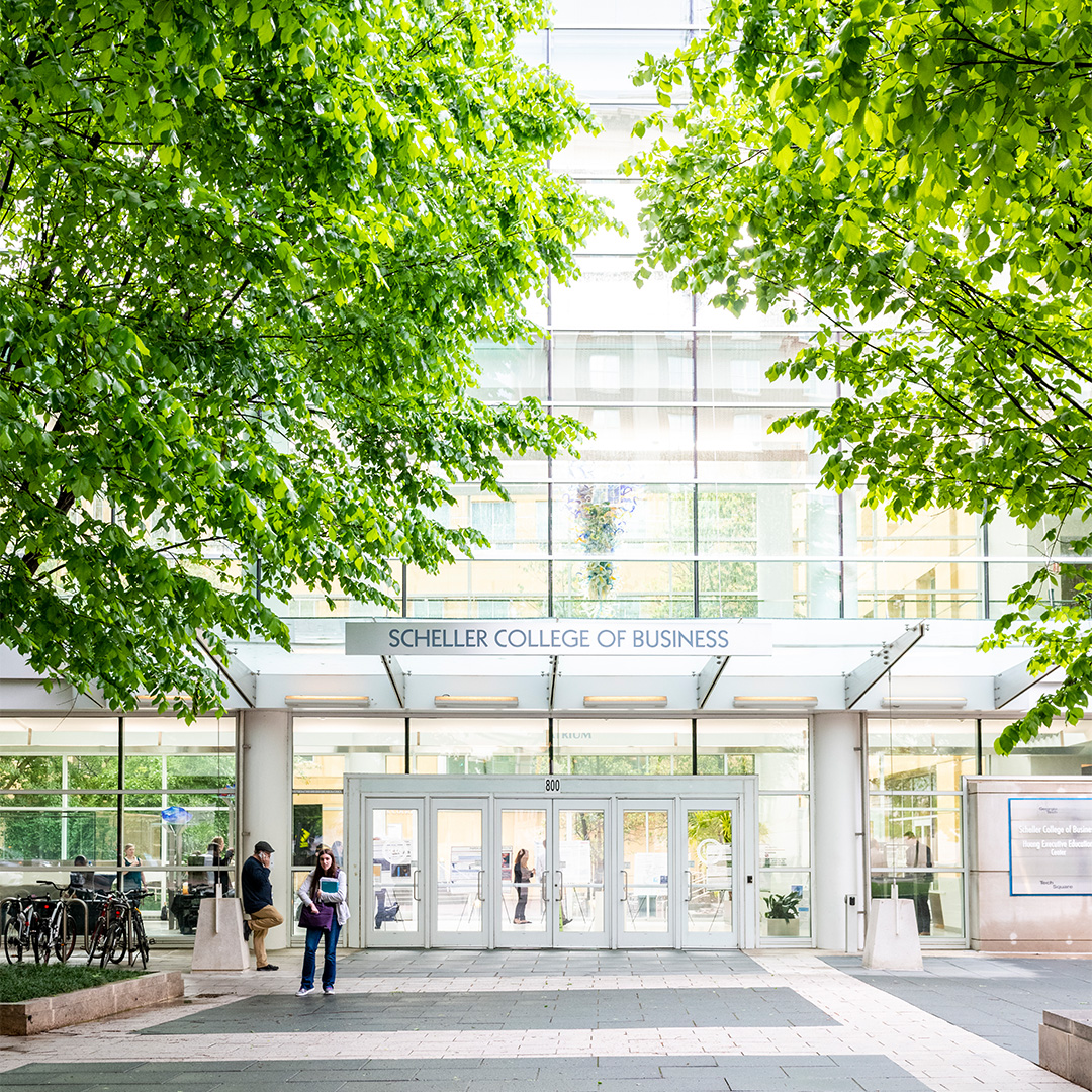 The exterior of the Scheller College of Business main entrance framed by green, leafy trees