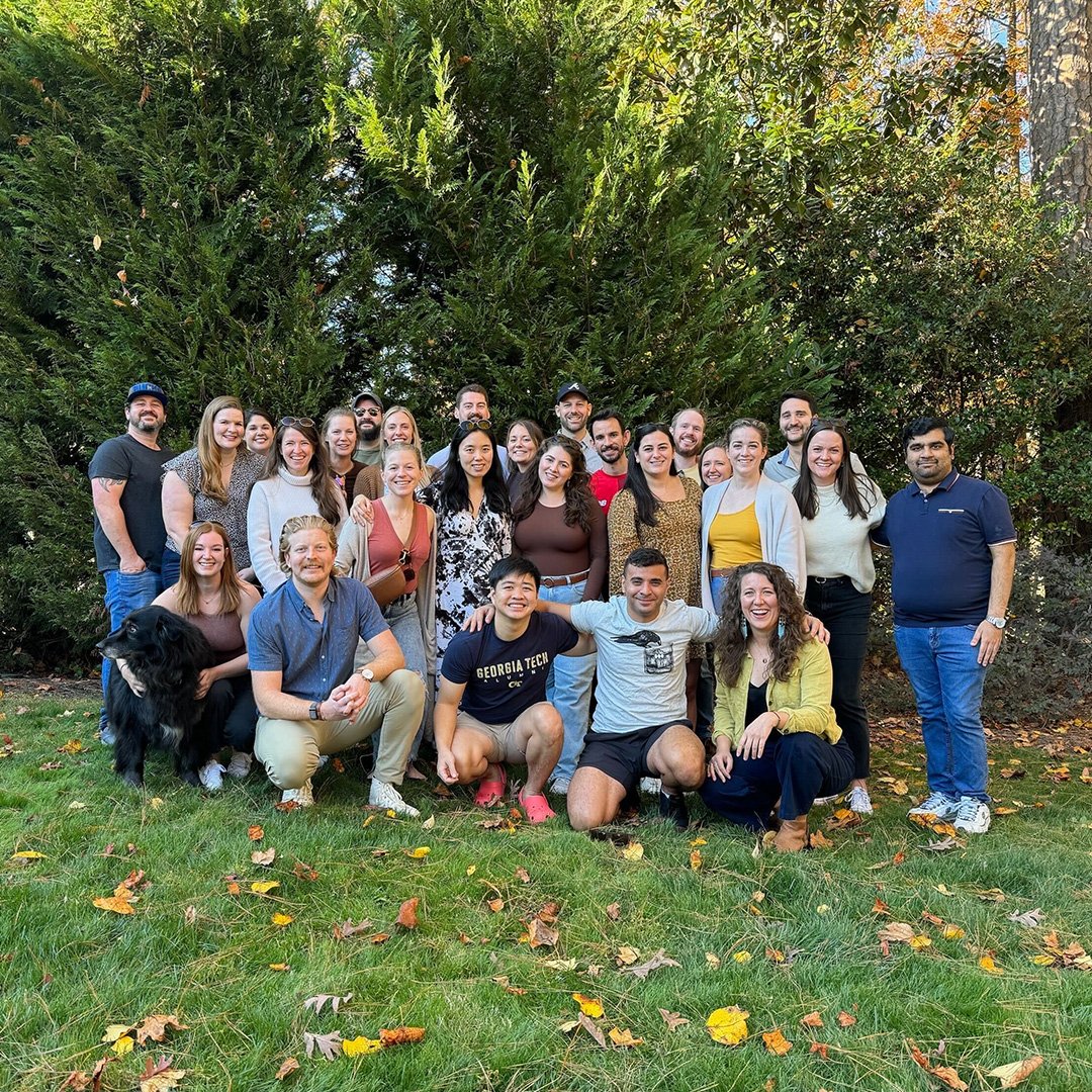 A group of women and men smile outside