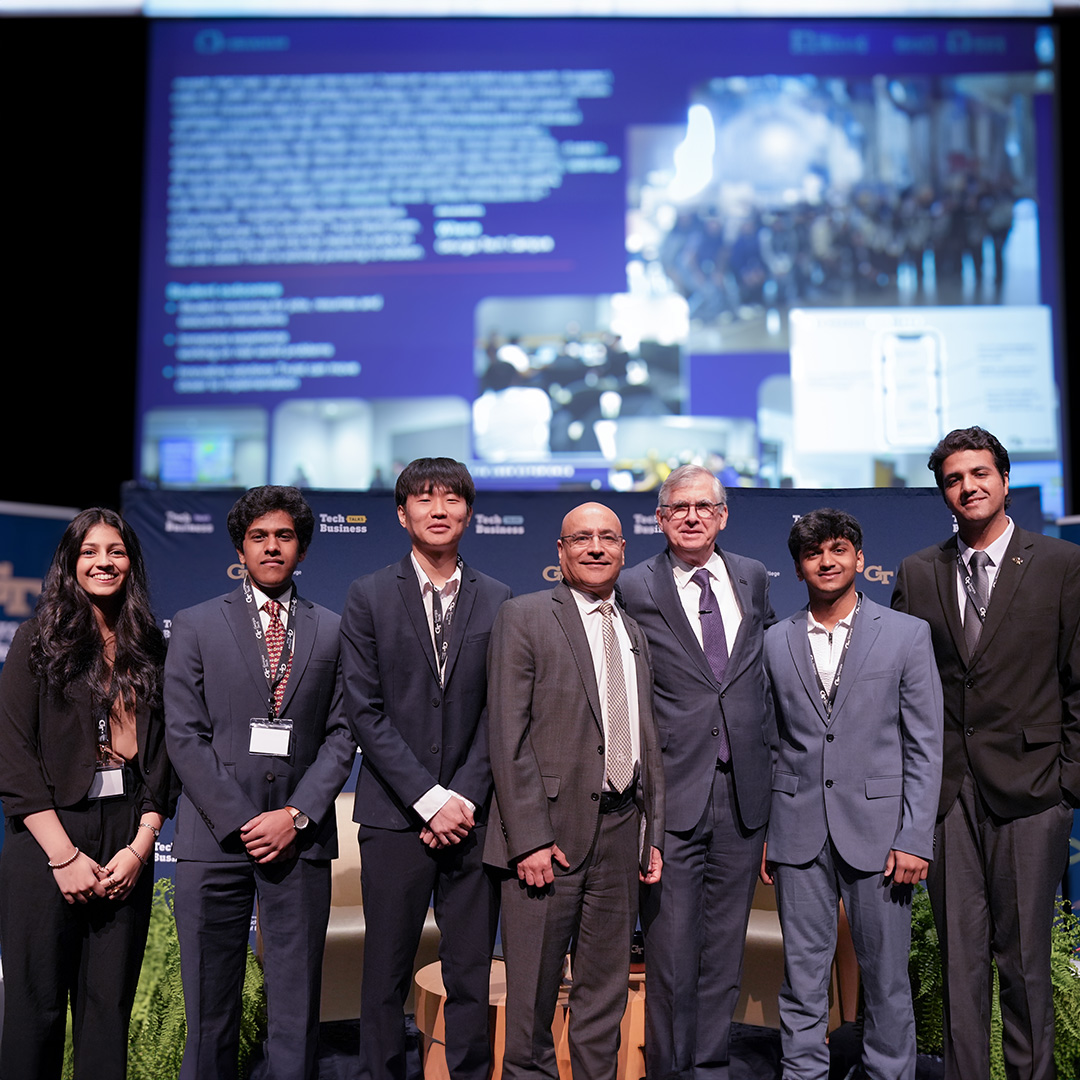 Students and professionals stand on a conference stage