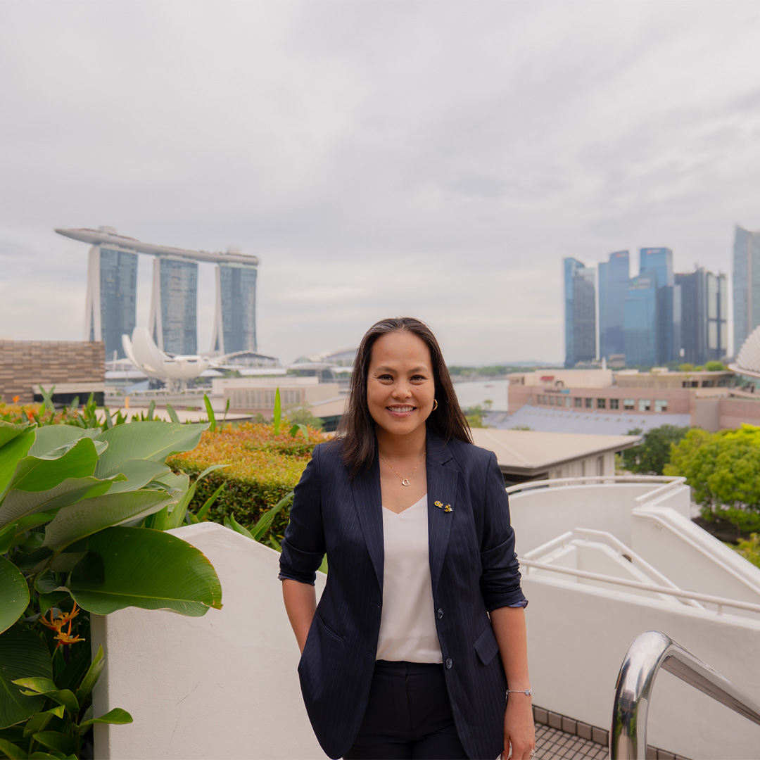 Hawn Nguyen-Loughren, Executive MBA ’25, stands outside with a city-scape in the background