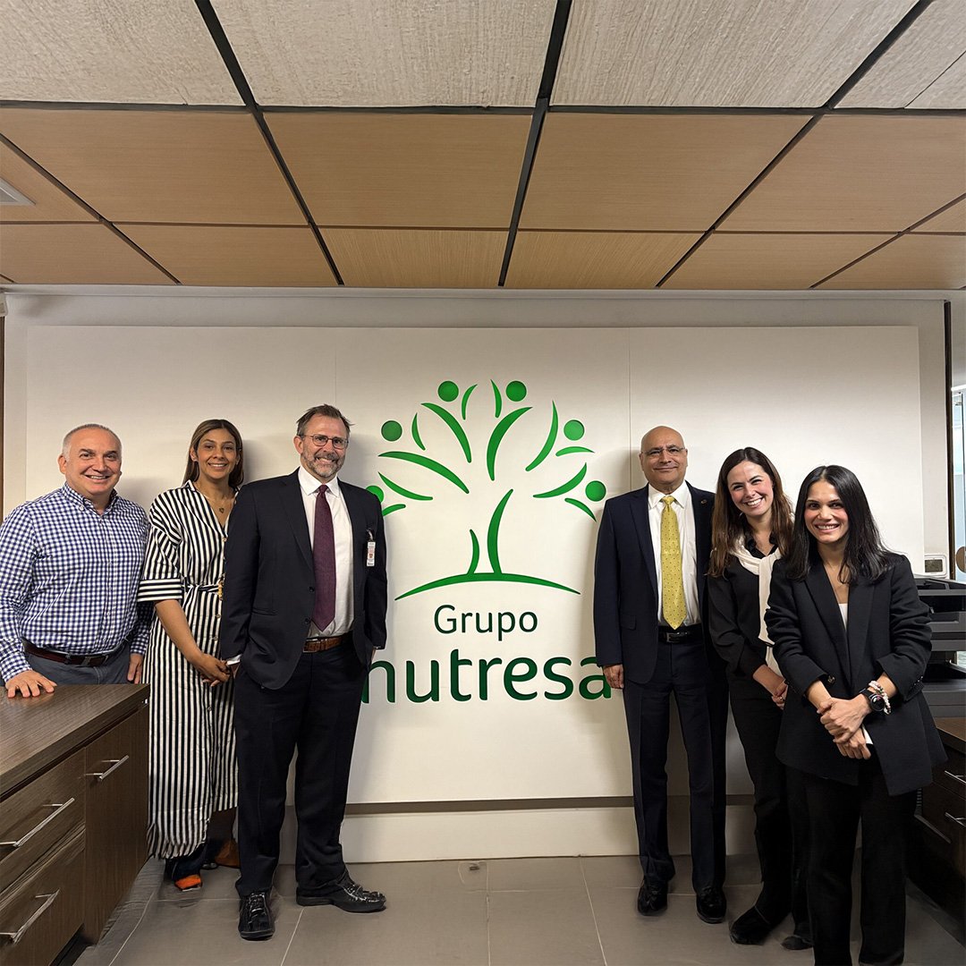 A group of women and men stand in front of a "Grupo Nutresa" sign